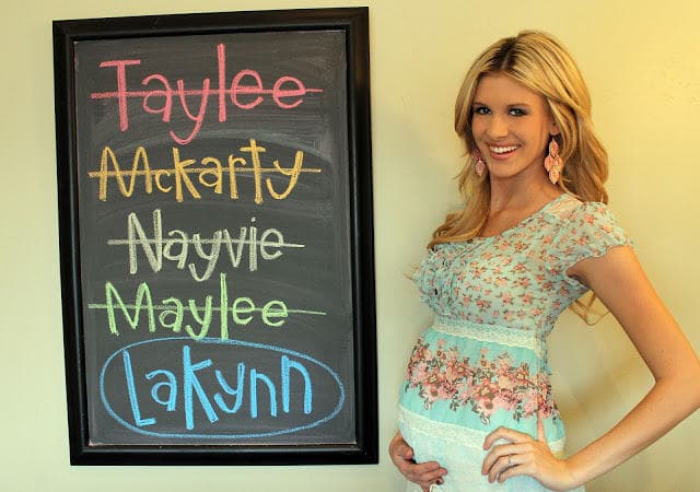 Blonde pregnant woman with baby name chalkboard
